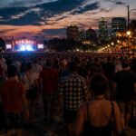 Pubblico a un grande concerto serale con la città illuminata sullo sfondo